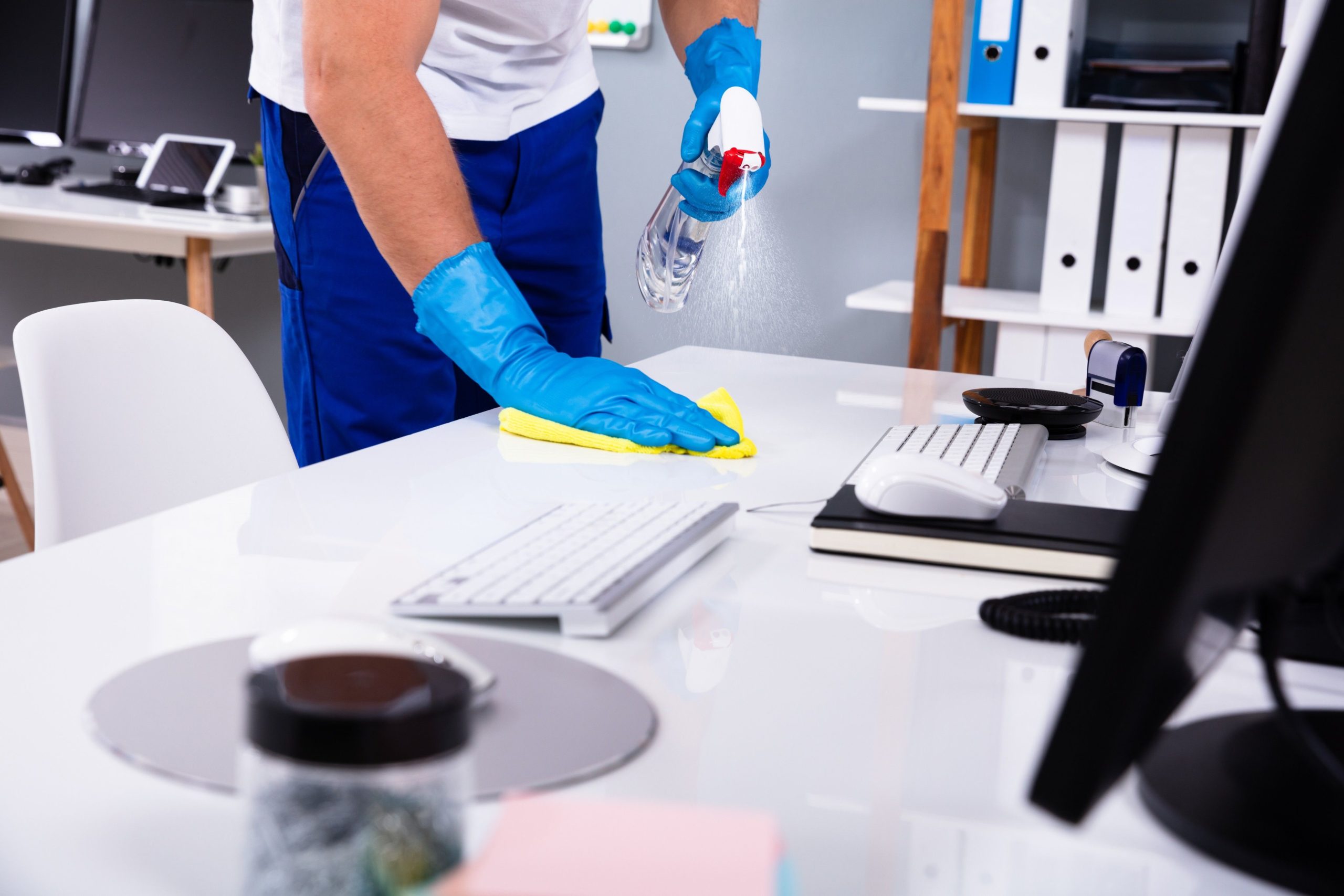 Close up blue latex gloves cleaning the surface of office equipment with disinfectant