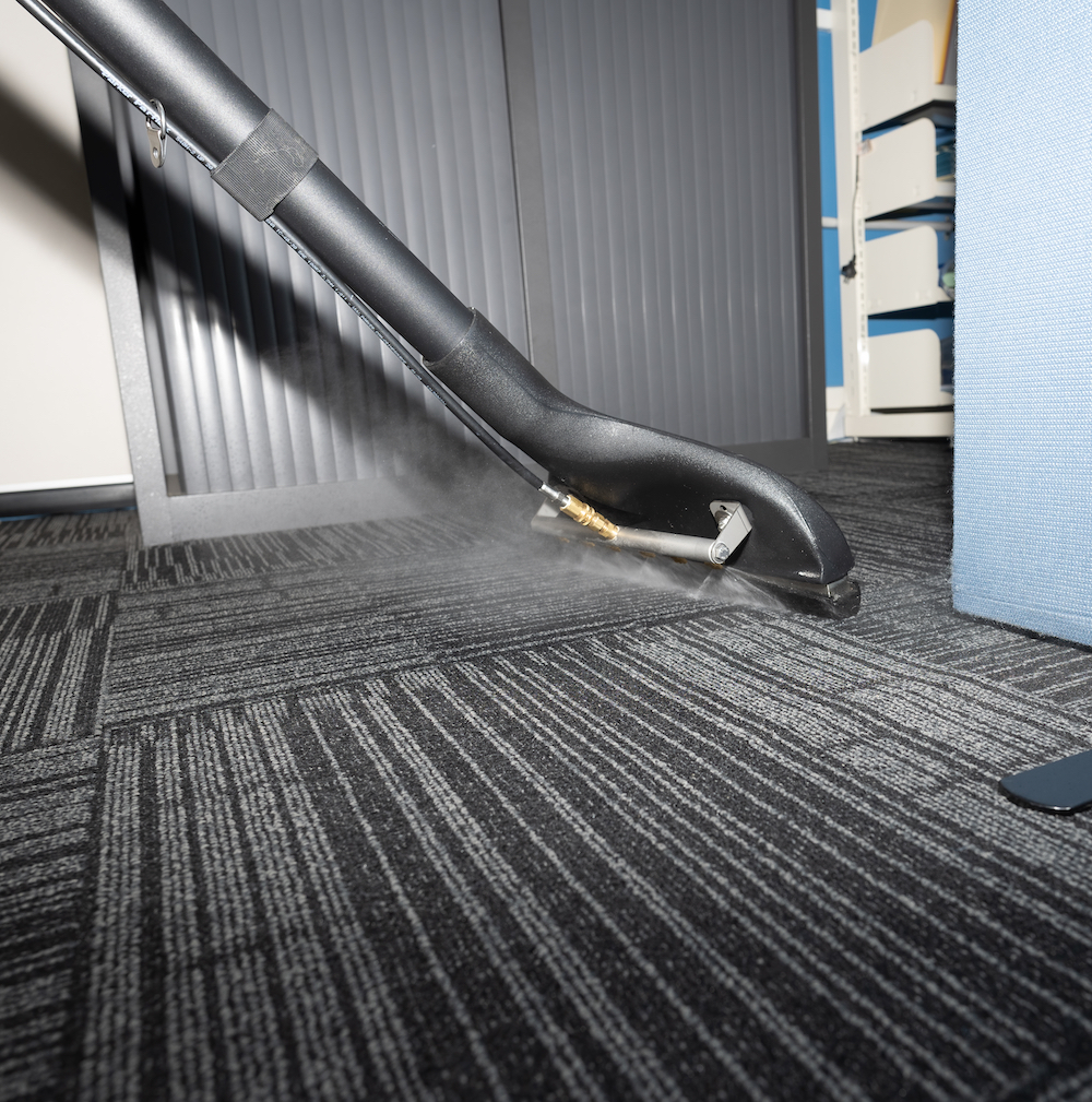 Close up of commercial vacuuming cleaner being used on office carpet.